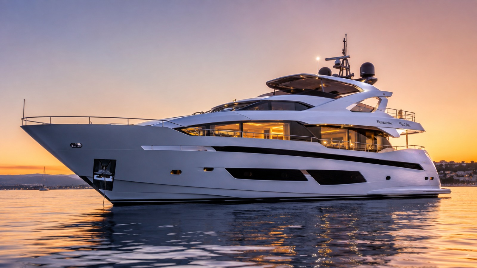 A motor yacht at anchor in calm water at sunset
